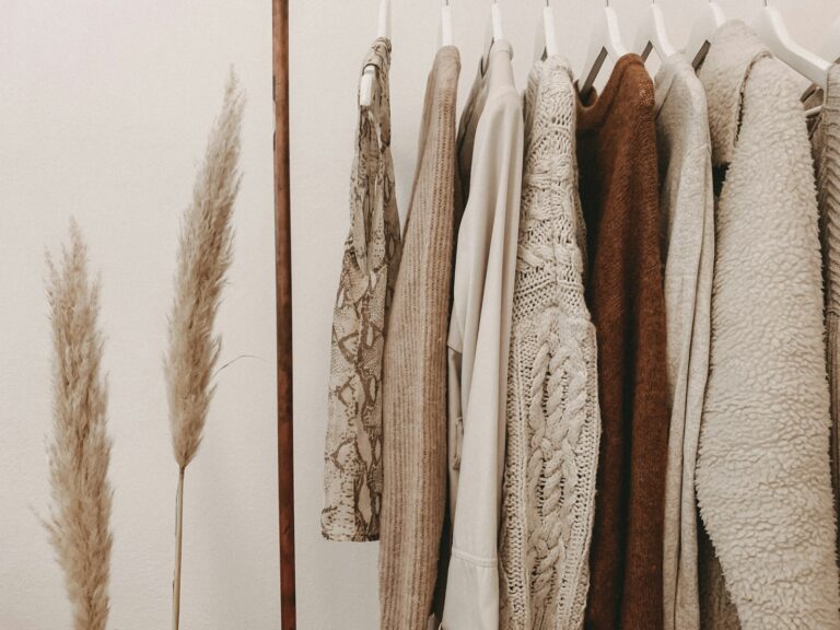 Neutral-toned fall sweaters and clothing hanging on a rack