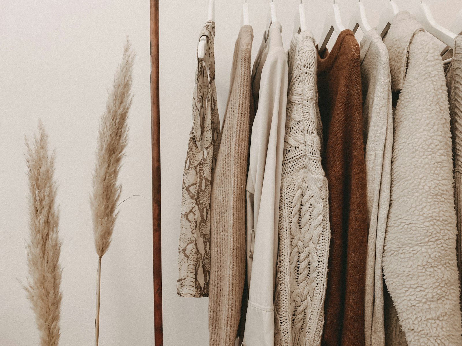 Neutral-toned fall sweaters and clothing hanging on a rack