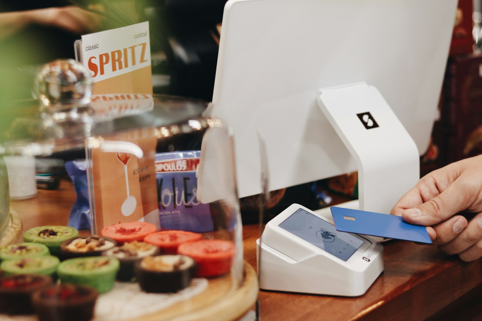 A customer tapping a credit card on a payment terminal at a checkout counter
