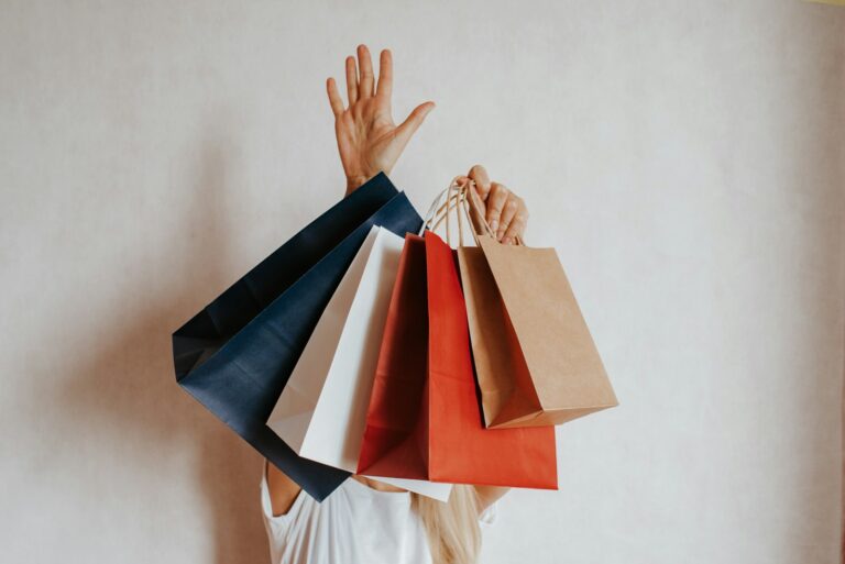 A person holding an armful of colorful shopping bags